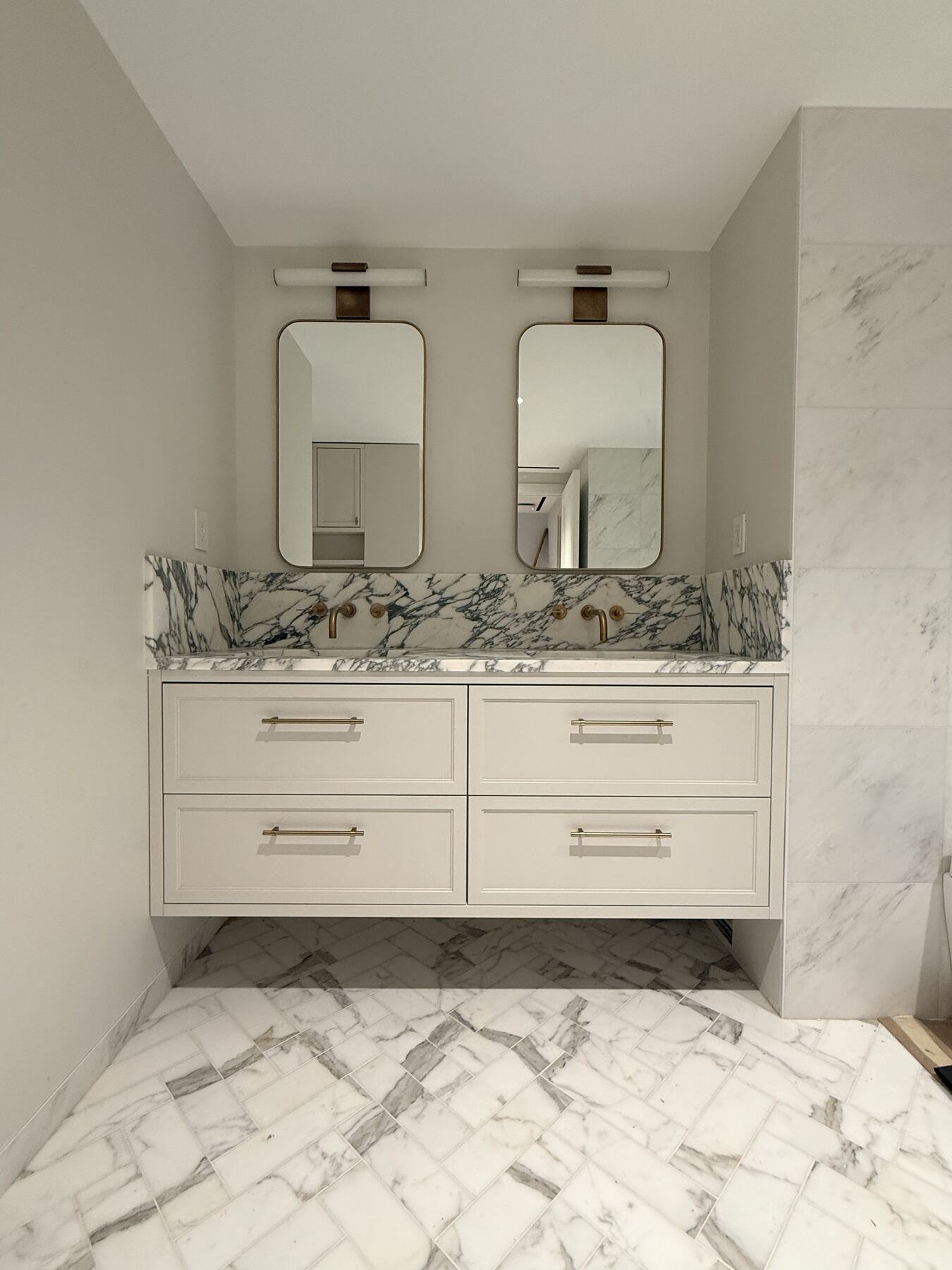 Floating double vanity with brass fixtures and marble top
